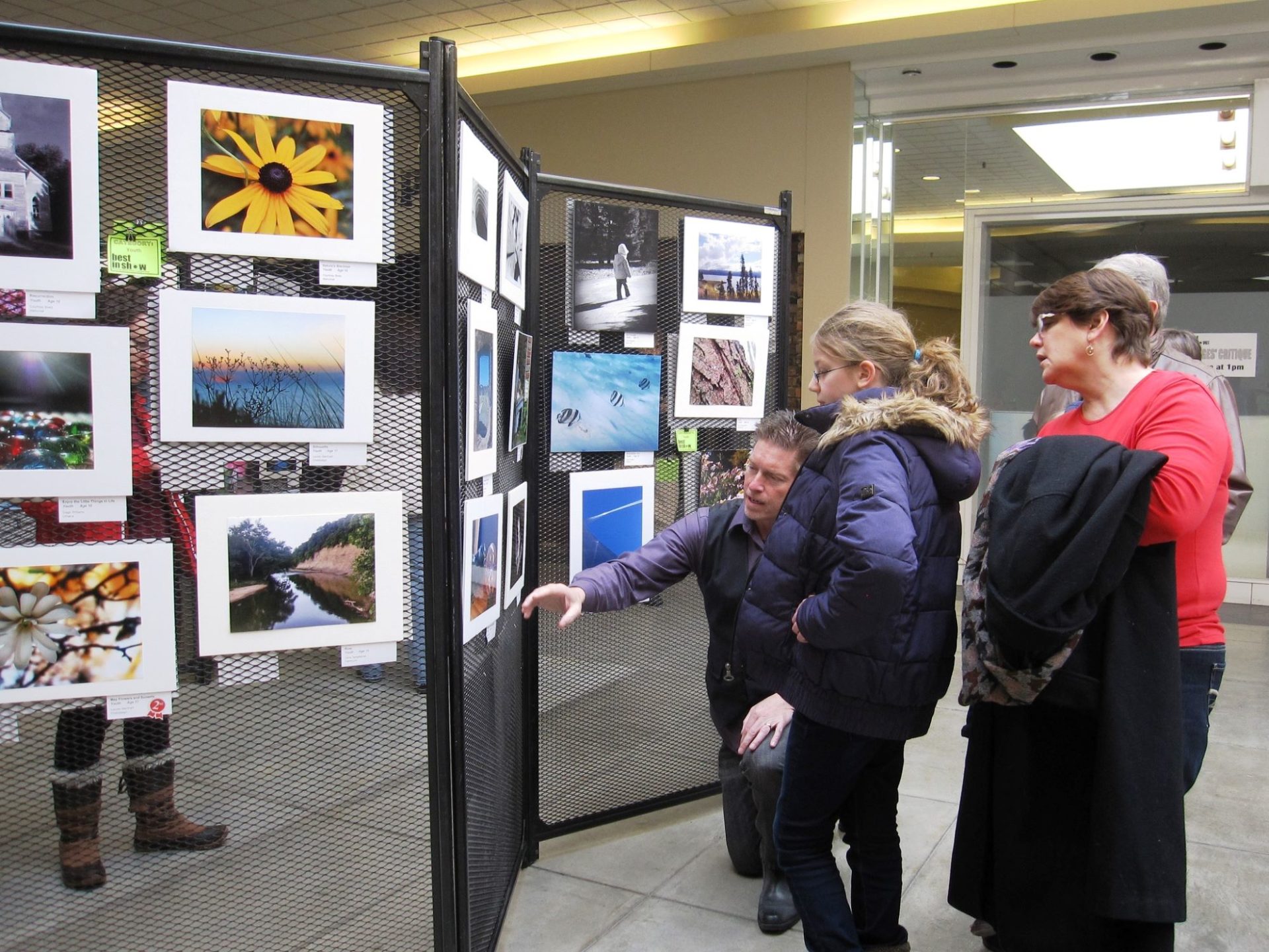 A group of people examining a display of photographs.