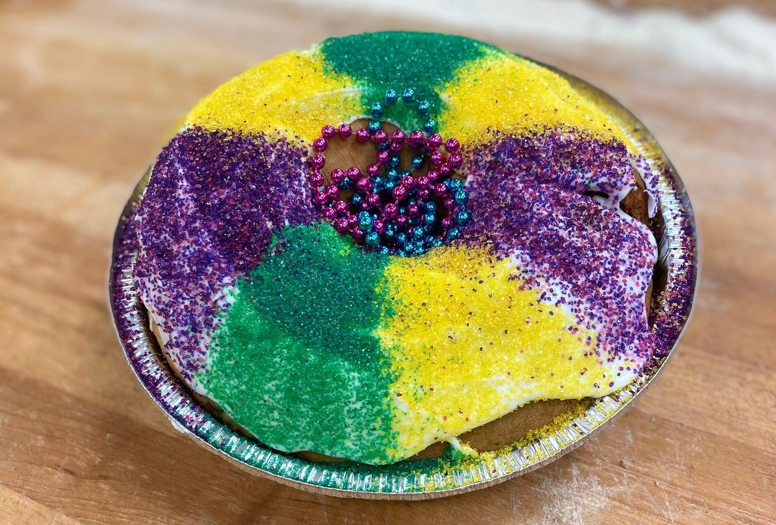 A circular cake with yellow, green, and purple frosting, and beads in the center.