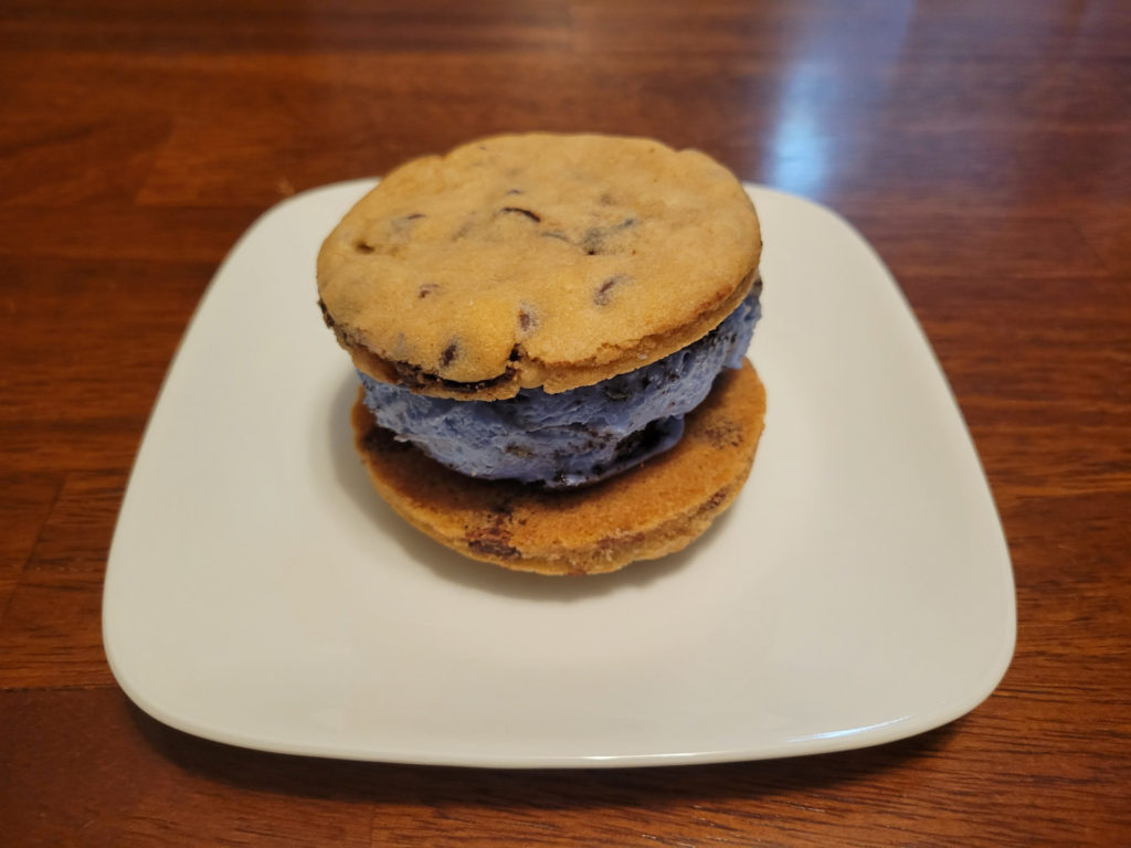 A cosmic cookie chocolate chip ice cream sandwich on a small, white plate.