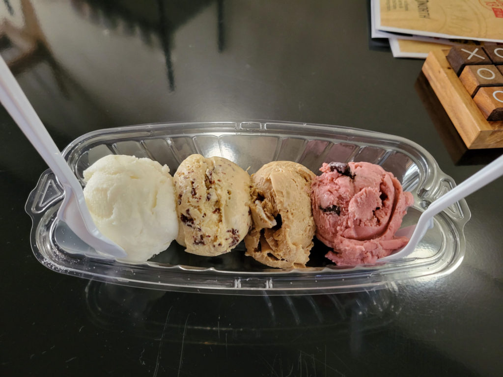 A plastic boat flight of two ounce ice cream scoops: (from left to right) limoncello sorbet, espresso stracciatella, fluffernutter, and black raspberry chip.