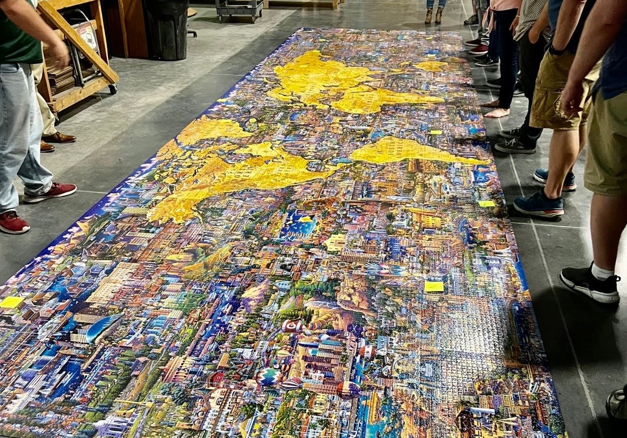 A large completed puzzle of a map of the world, laid out on a concrete floor.