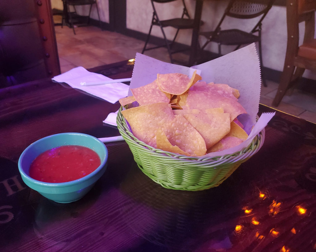 A basket of chips and salsa on a table.