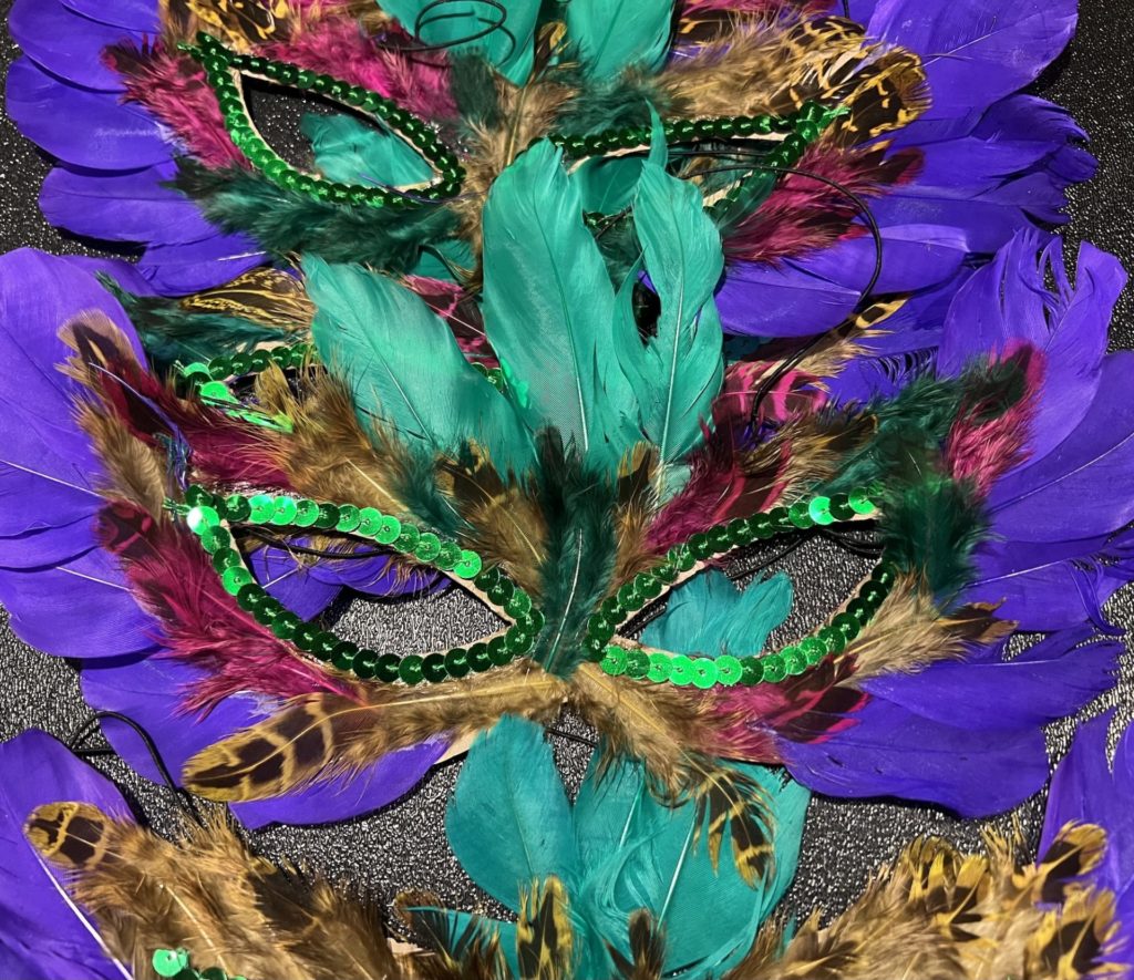 Feathered masks for Mardi Gras. They have green and purple feathers, and green sequins around the eyes.