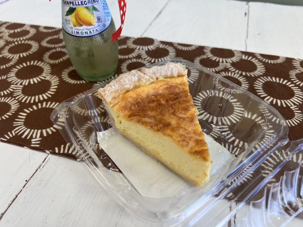 A slice of quiche in a plastic take away container.