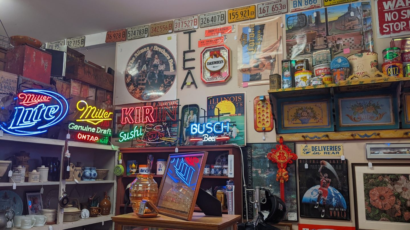 Another view of the inside of Antiques and more on Staley Road. The top of the wall has old license plates, neon beer signs, old cracker tins, and grated pictures. 
