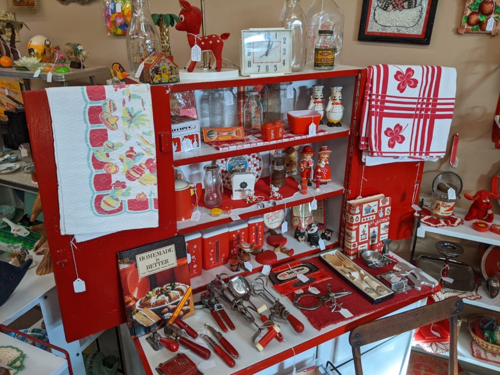 A room of Antique kitchen ware. Most of the colors in this picture are the red section. They are all displayed on a red and white cabinet. 