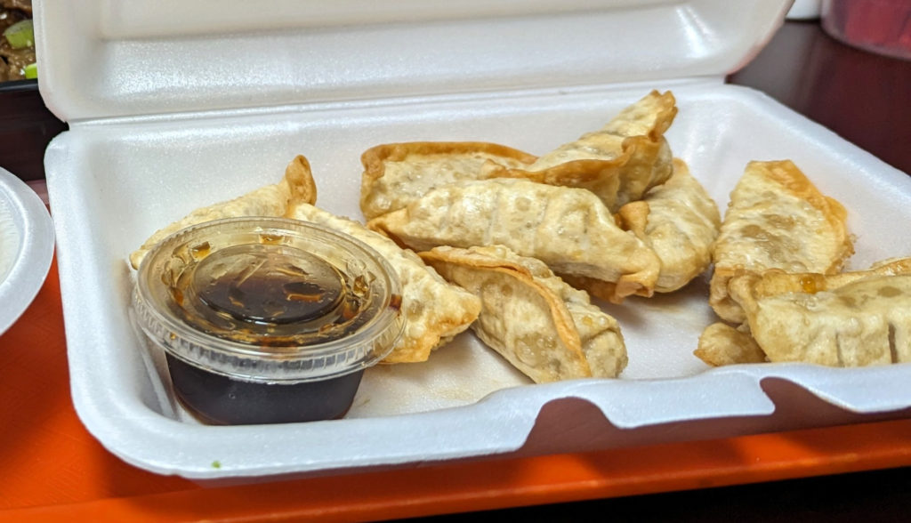 The dumplings at Cravings beside a plastic cup of soy sauce.