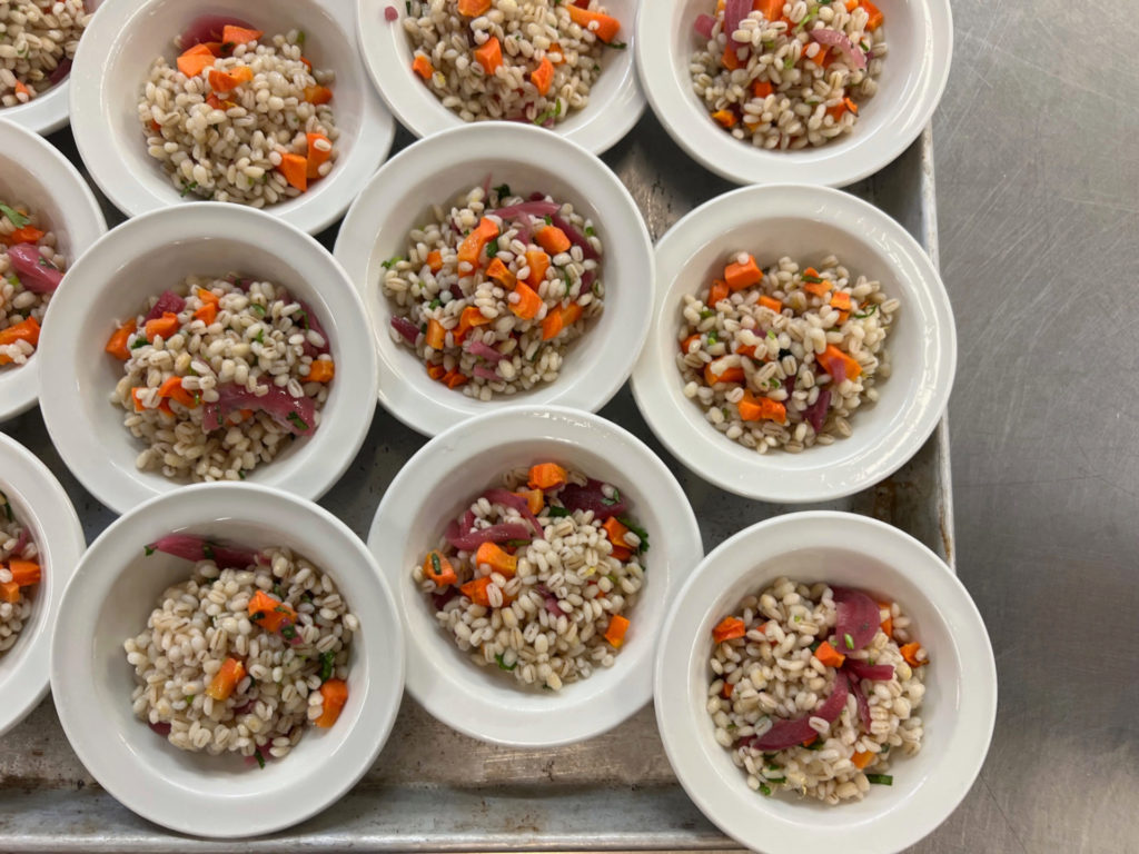 Several small bowls of farro salad with red onions and carrots.