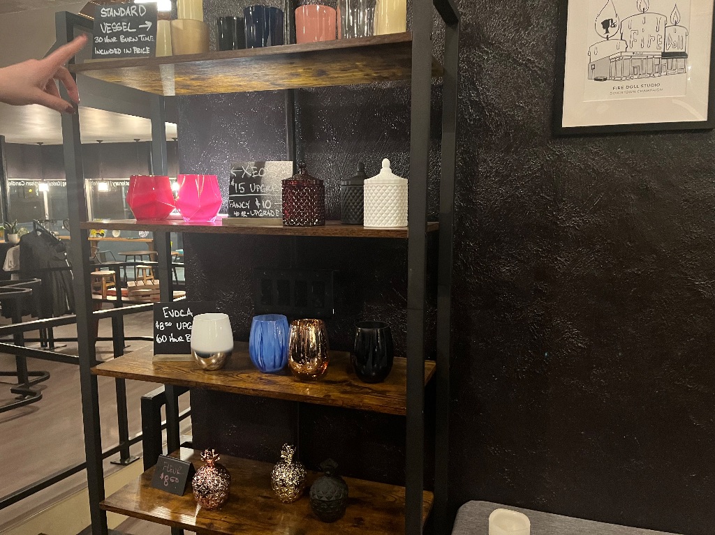 A shelf with various glassware on a shelf against a black wall. 