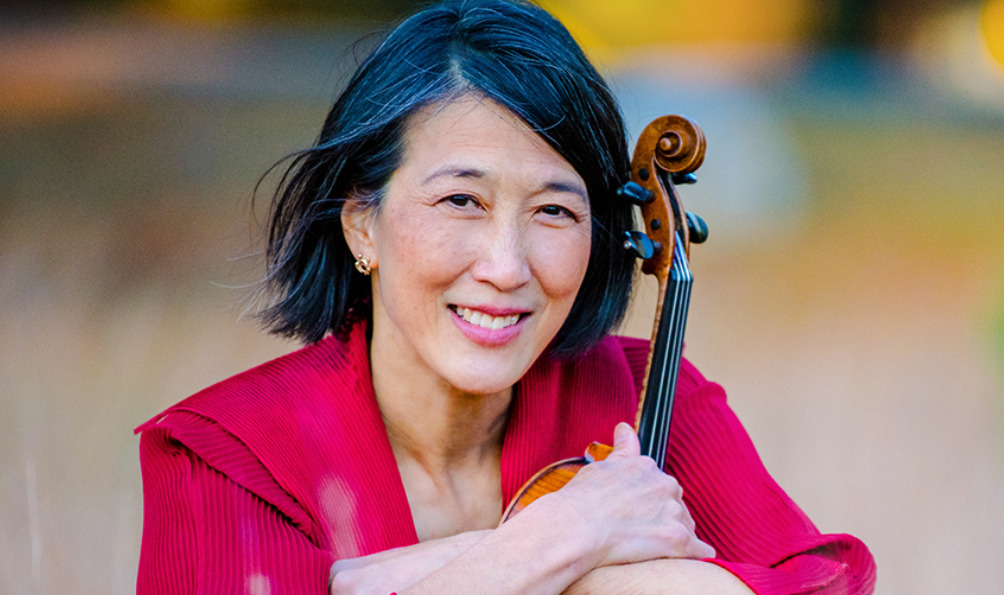 Headshot of an Asian woman with chinlength black hair. She is wearing a red blouse and holding the neck of a violin.