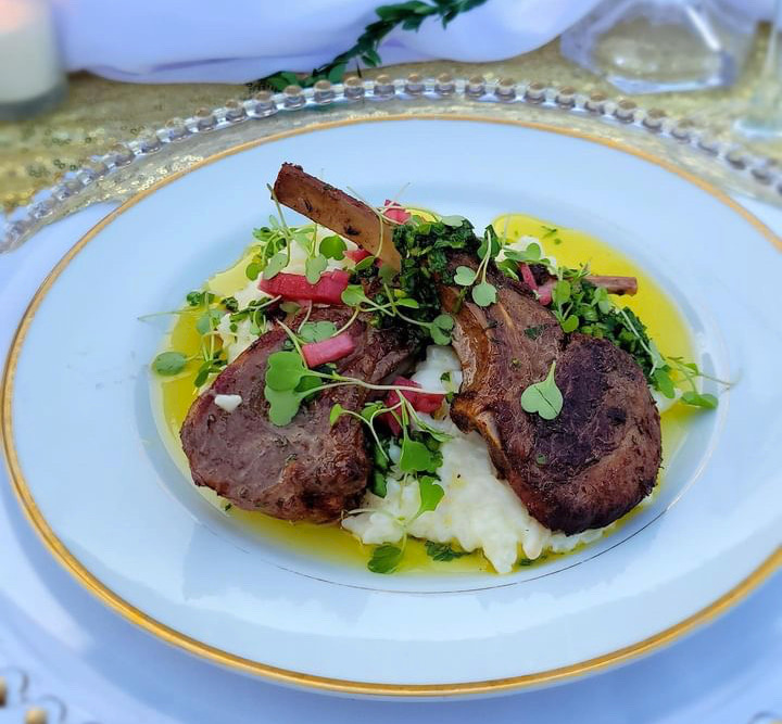 Two lamb chops over mashed potatoes and microgreens.