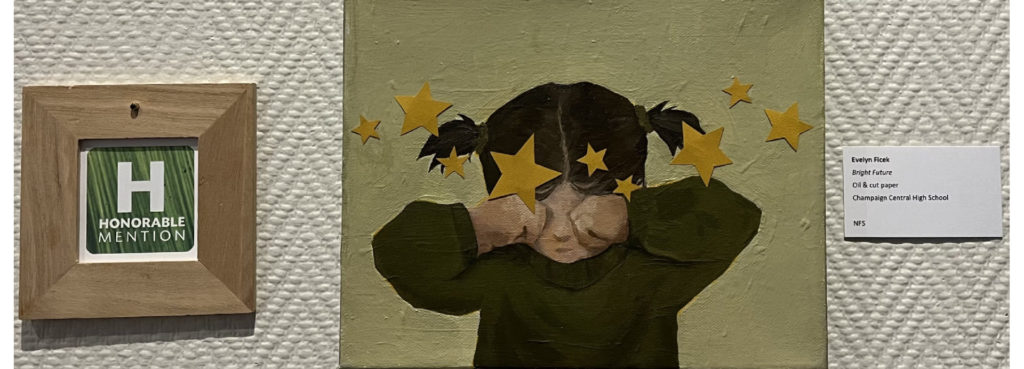 Photo of a painting of a young girl wiping her eyes. She has brown hair and there are bright yellow stars cut out of paper all around her face and hands.