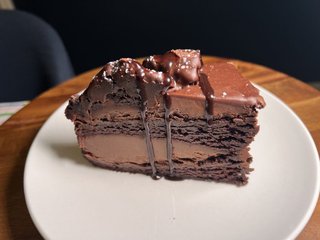 A large layered slice of chocolate cake on a white plate