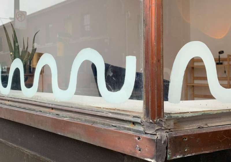 The corner of a store window, with white squiggly lines painted along the window ledge.
