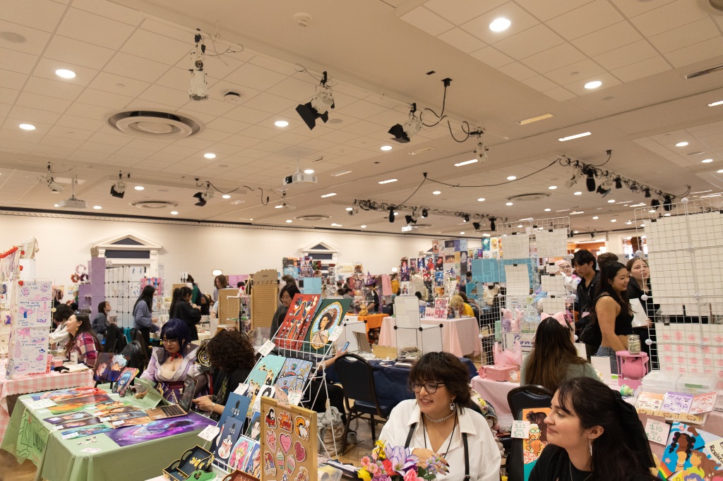 A ballroom in the U of I union is filled with over 50 vendors and their tables displaying keychains, posters, soaps, and stickers from various anime and comics.