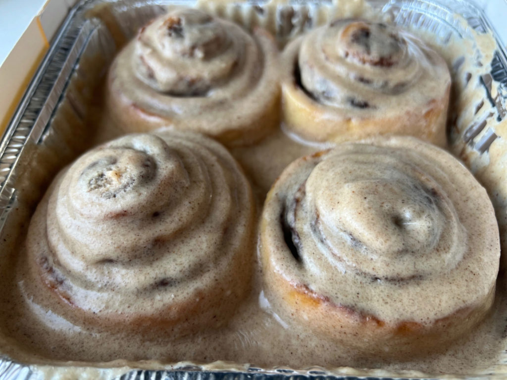 Four cinnamon rolls in a tin foil container.