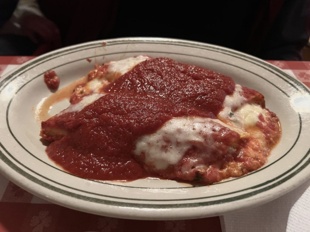 Two large manicotti on a plate smothered in marinara
