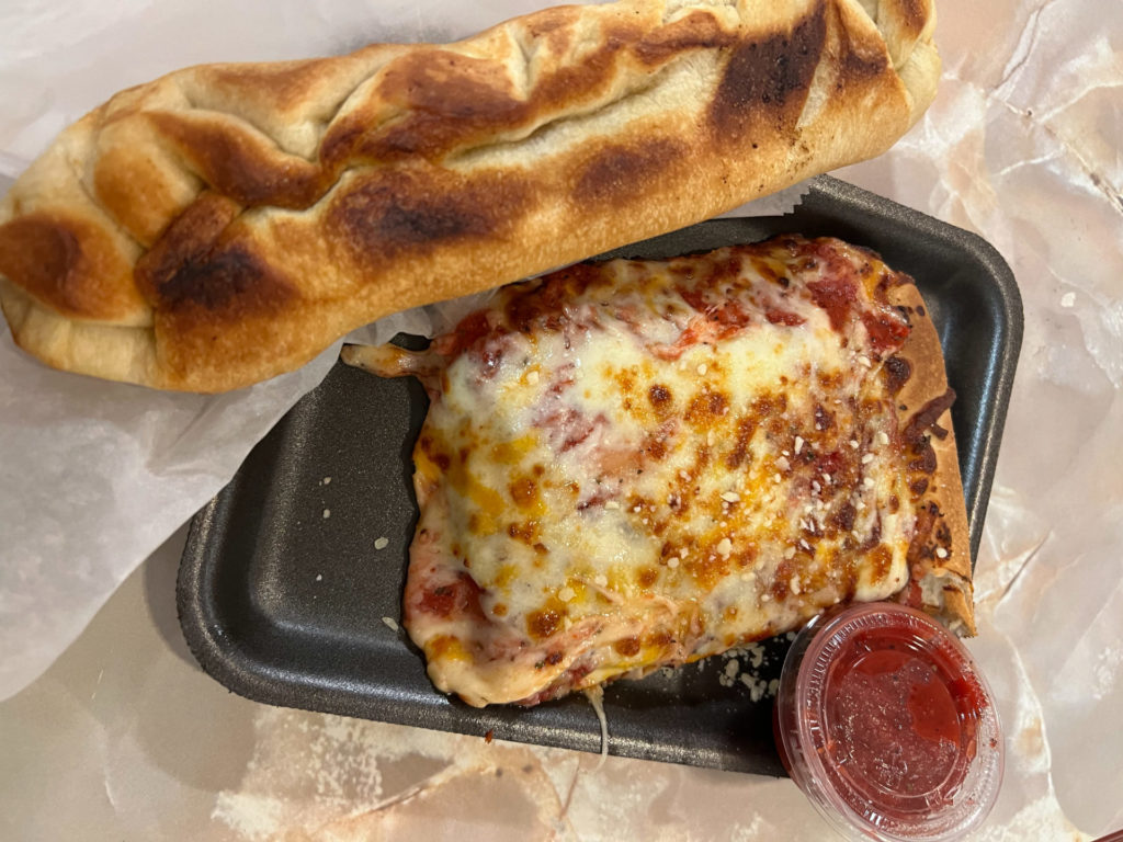A rectangular slice of pizza with a big baguette from Mia Za's in the Union.
