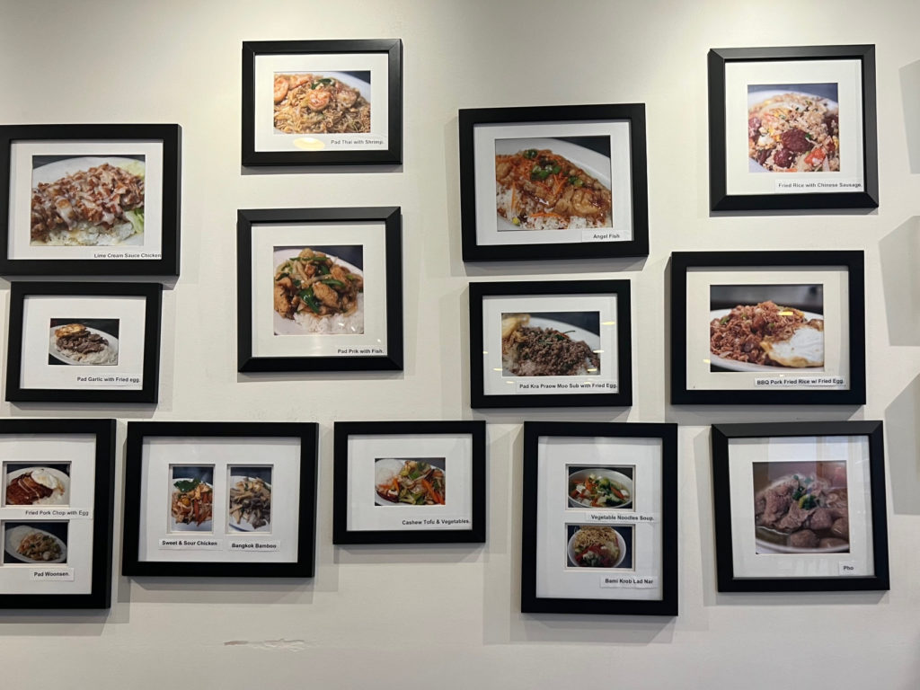 A gallery wall of framed photos of Thai food labelled in English.