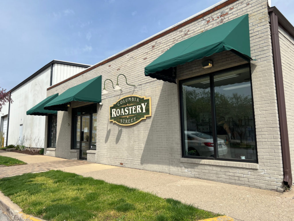 The exterior of Columbia Street Roastery with green awnings and a sign.