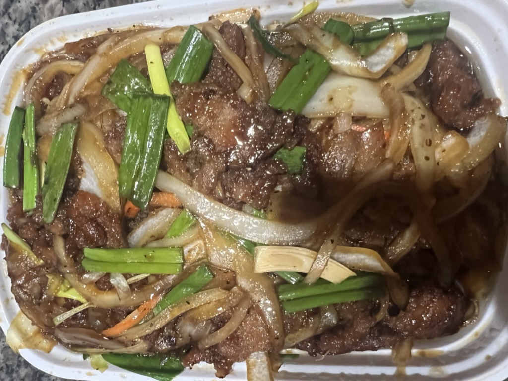 A takeout orde rof Mongolian beef with onions.