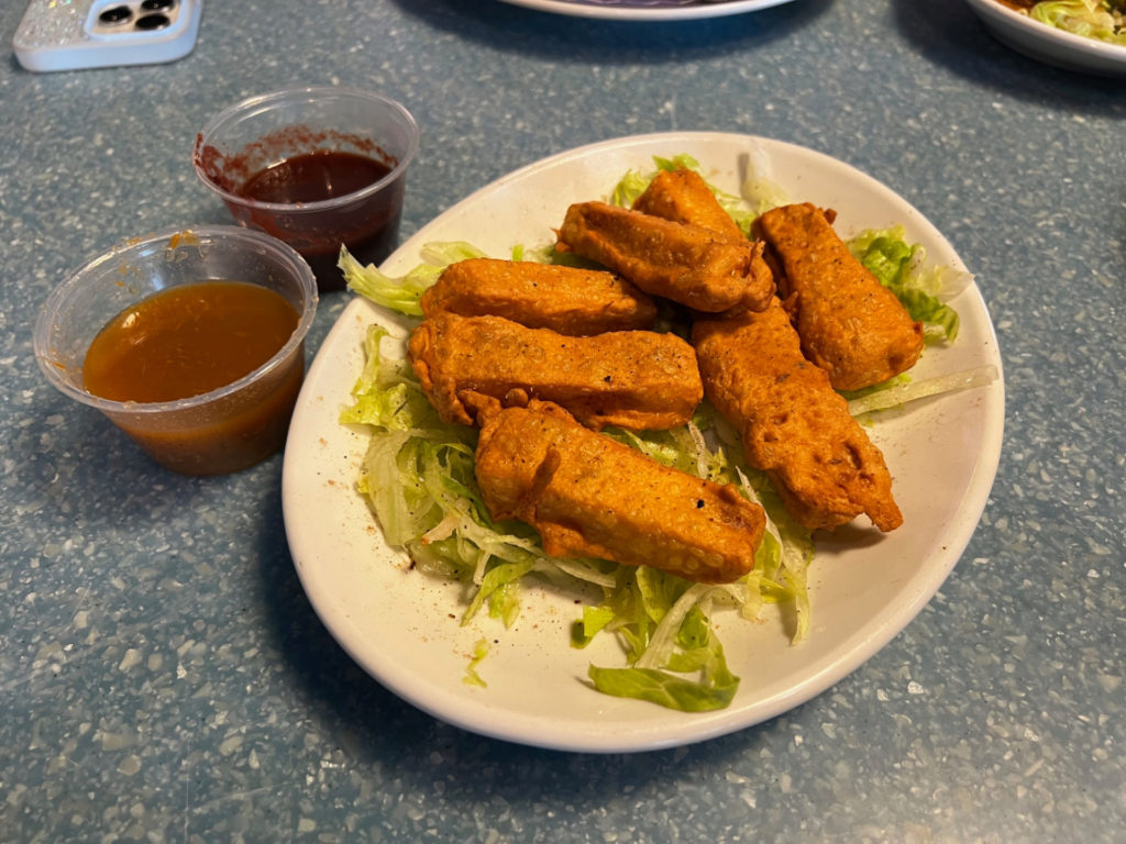 Paneer pakoda on a bed or lettuce with two side sauces.