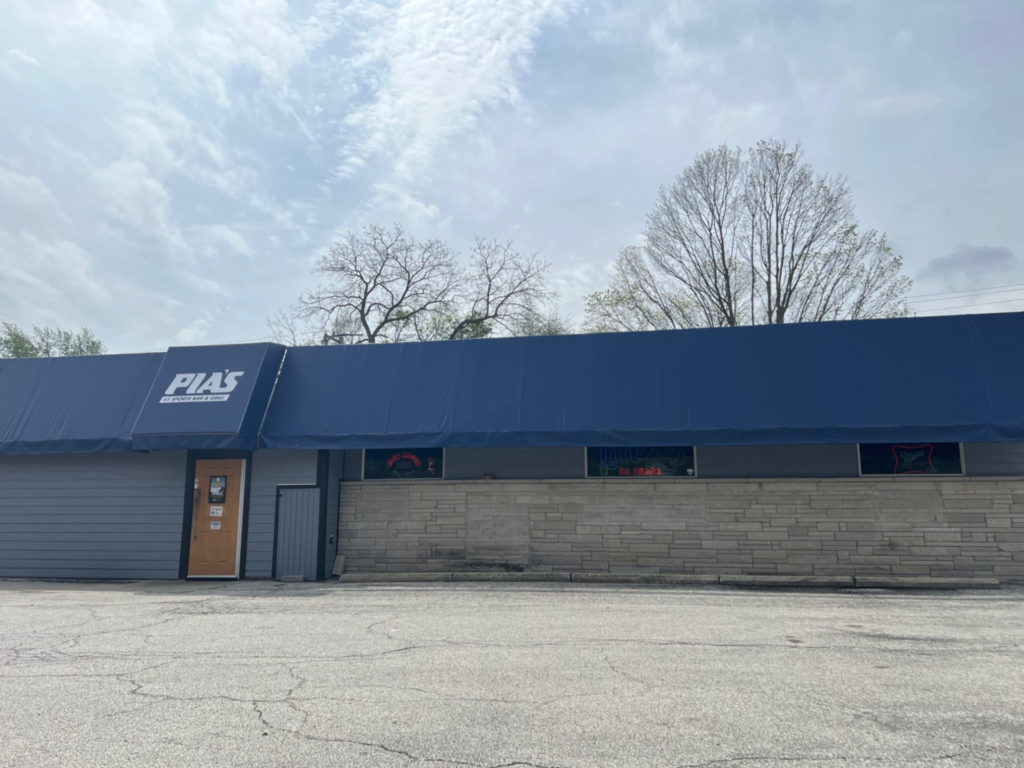The exterior of Pia's Sports Bar & Grill in Champaign has a dark blue awning along a long one-story building. No cars are parked out front.