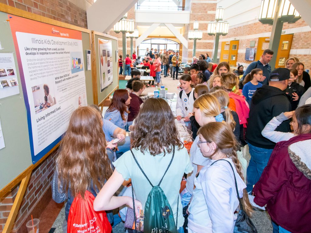 A crowded hallway with students standing in front of giant information board. 