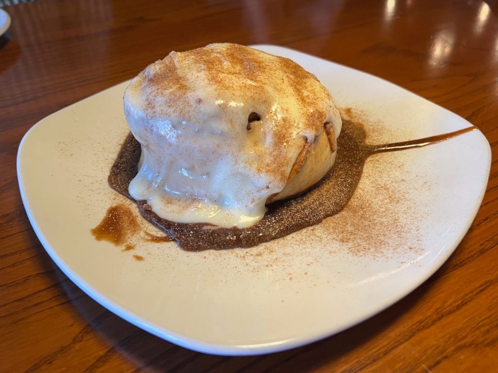 Cinnamon roll topped with a thin cream cheese sauce topped with cinnamon sugar.