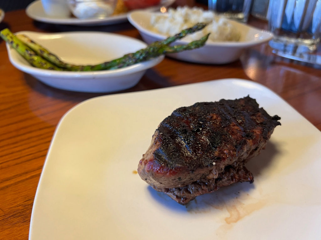 A charred filet mignon on a white plate.