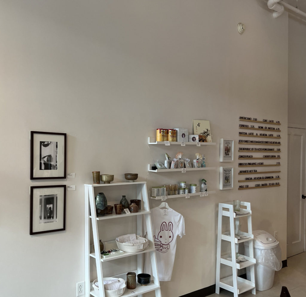 A white interior with white shelves holding art and merch for sale.