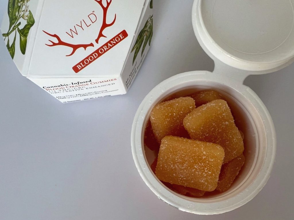Wyld gummies unboxed and the white container opened showing orange rectangular gummy candy.