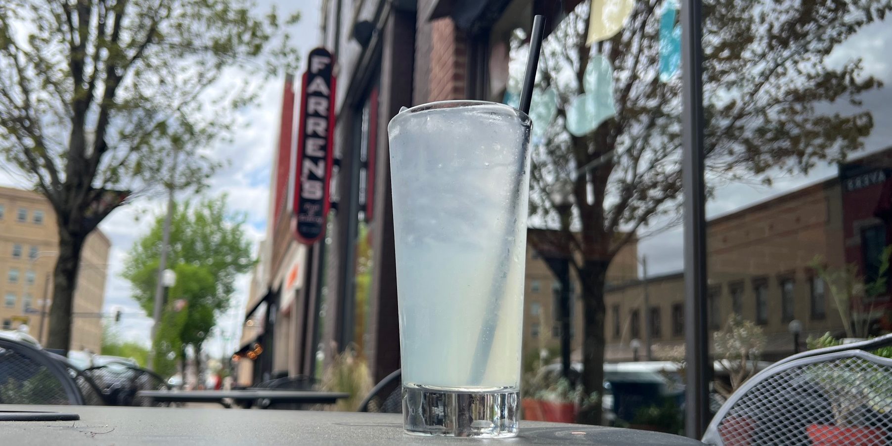 A Collins glass with a light green iced drink outside of Farren's Pub on a spring afternoon in Downtown Champaign.