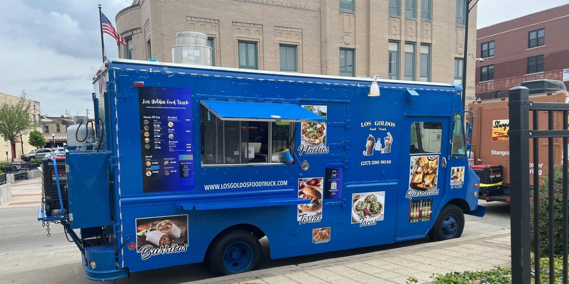 A blue food truck named Los Gordos is parked on the curb of Neil Street in Downtown Champaign on a cloudy spring day.