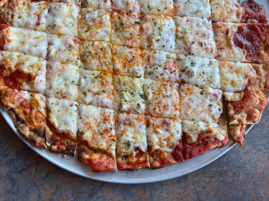 A tavern-cut thin-crust pizza by Old Orchard Lanes & Lines on a metal tray.