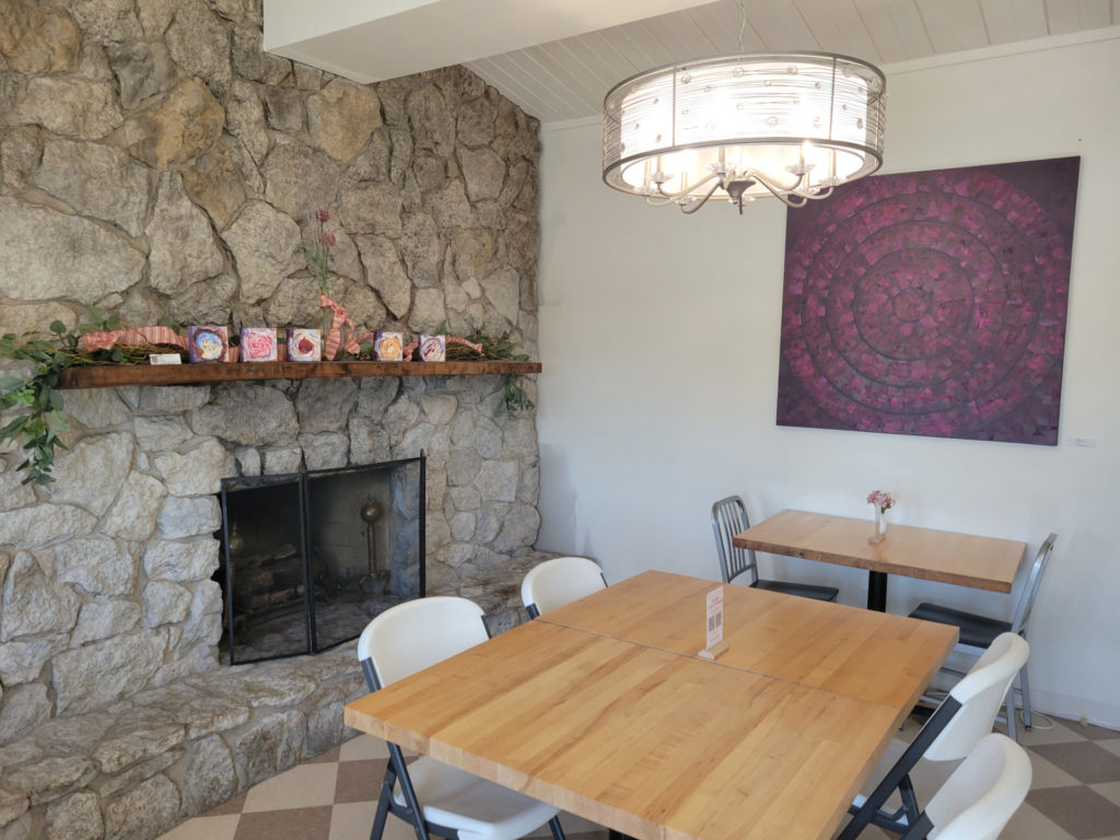 The interior of RegCakes with a stone fireplace and multiple tables surrounded with chairs.