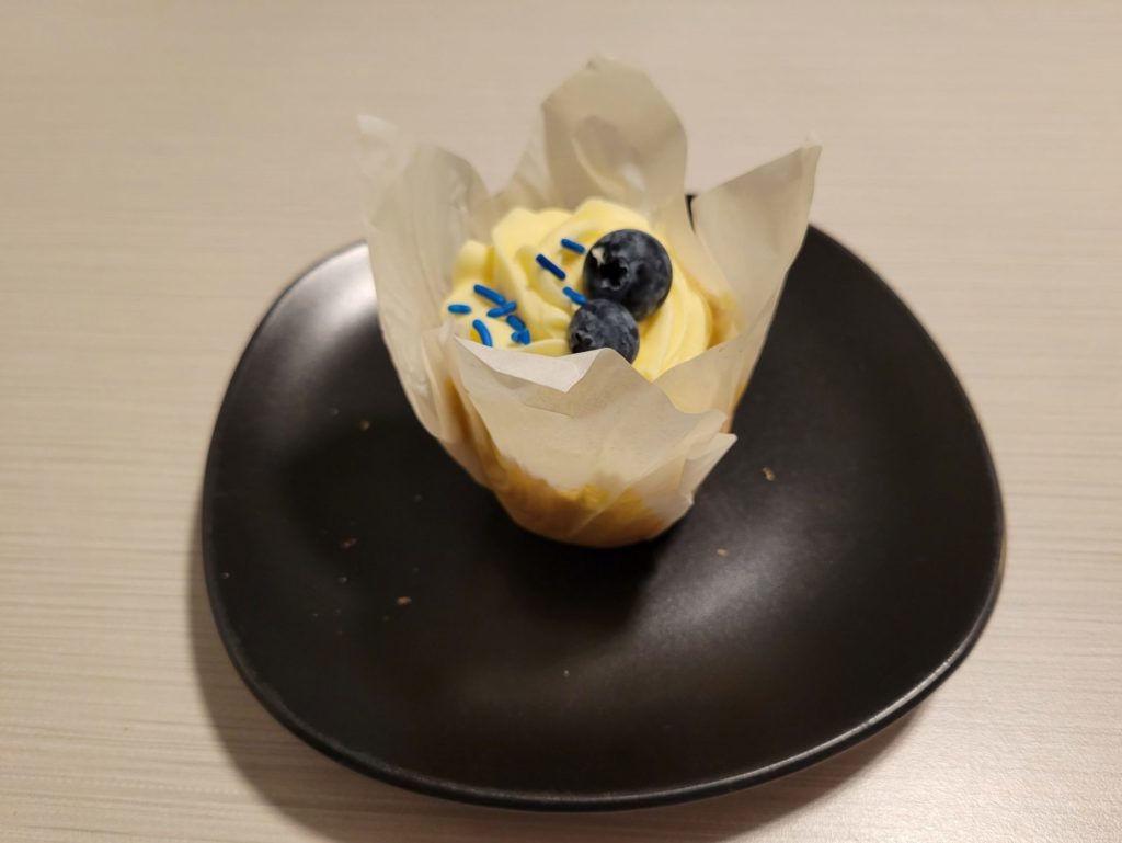 A lemon blueberry cupcake on a small black plate.