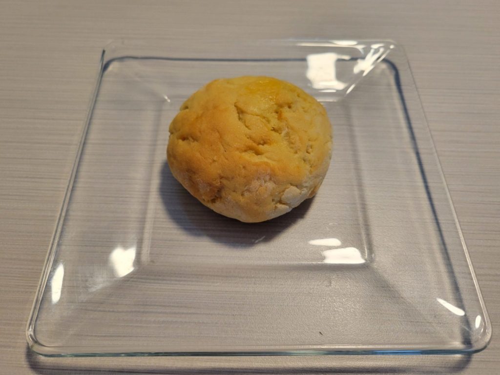 A brioche roll on a small glass plate.