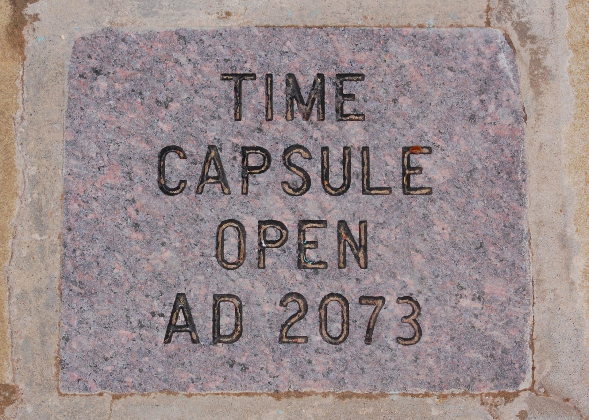 The top of a time capsule with the words TIME CAPSULE OPEN AD 2073 engraved into it