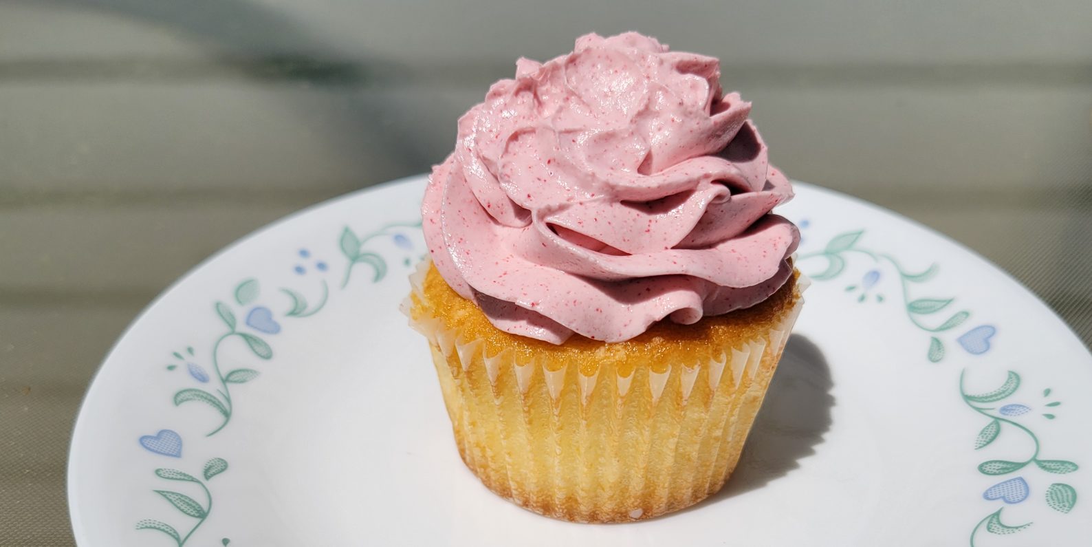 A lemon raspberry cupcake centered on a small white plate.
