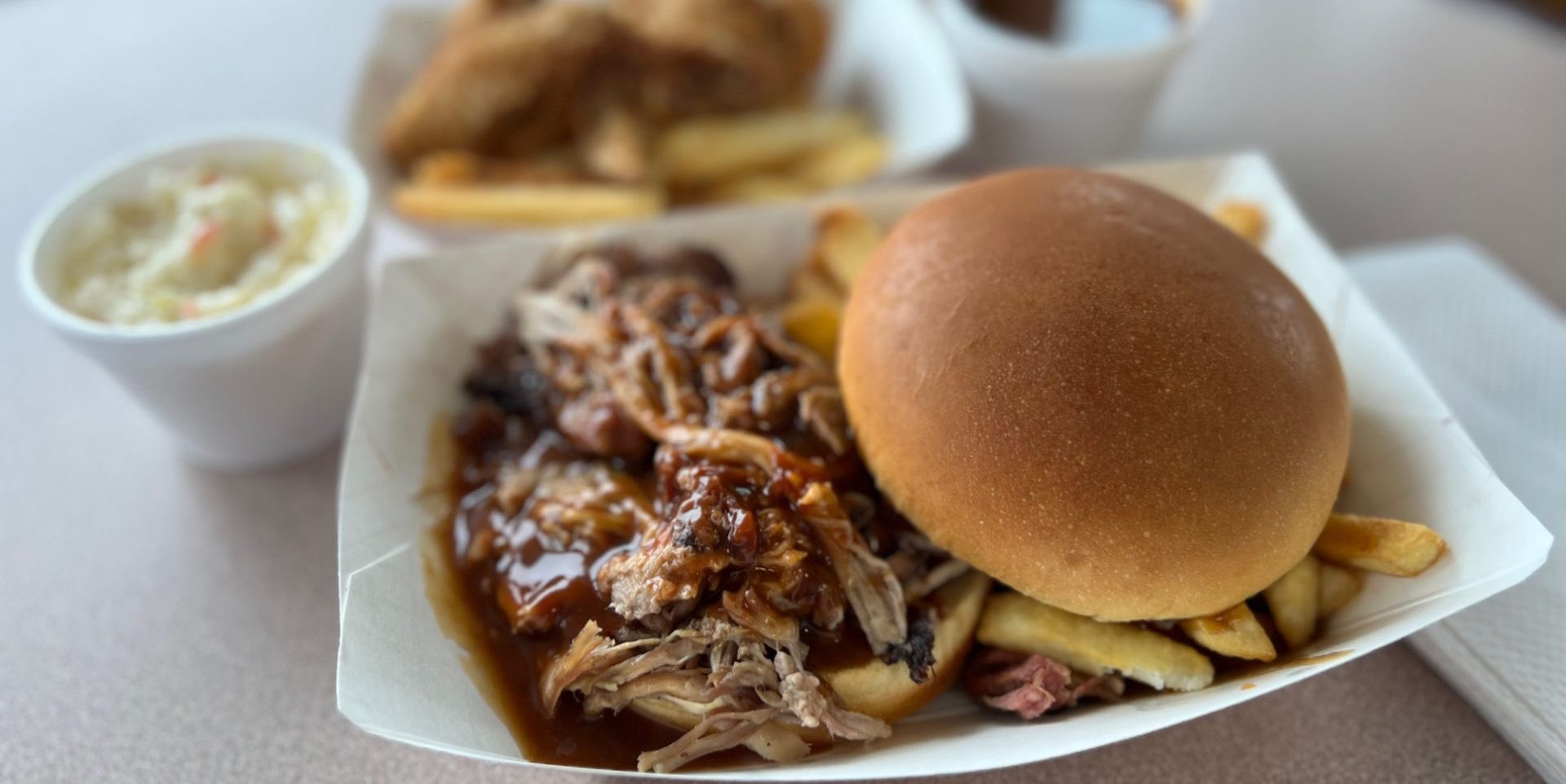 A pulled pork sandwich with sauce in a paper basket.